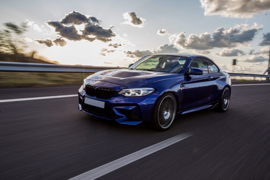 blue-sedan-car-driving-road-cloudy-weather-min