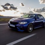 blue-sedan-car-driving-road-cloudy-weather-min